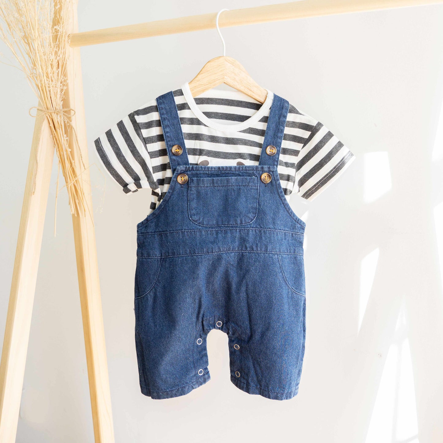 conjunto con tirantes vaquero azul y camiseta de rayas gris con oso en perchero de madera