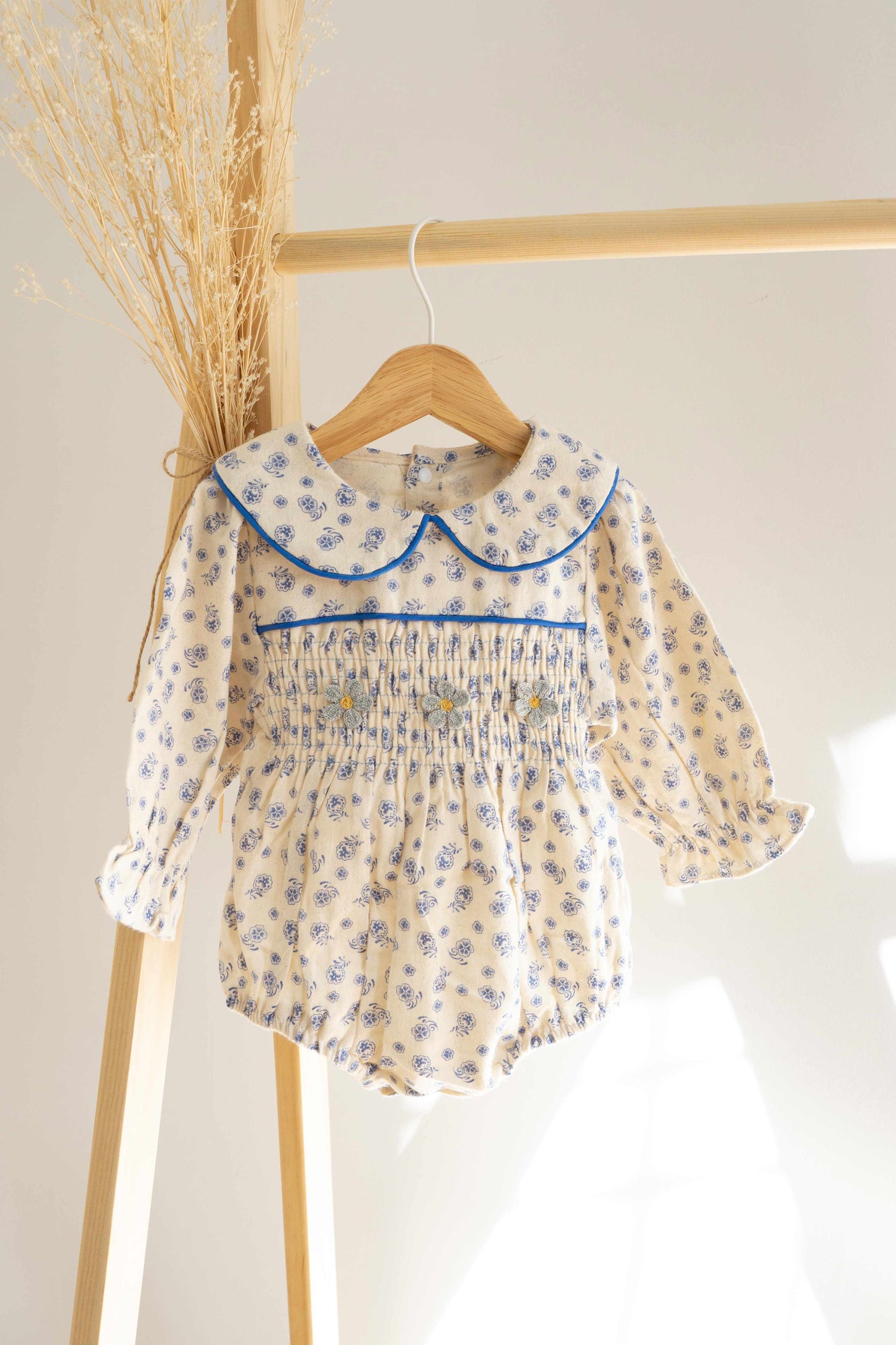 precioso vestido con estampado de flores azul colgado en perchero de madera 